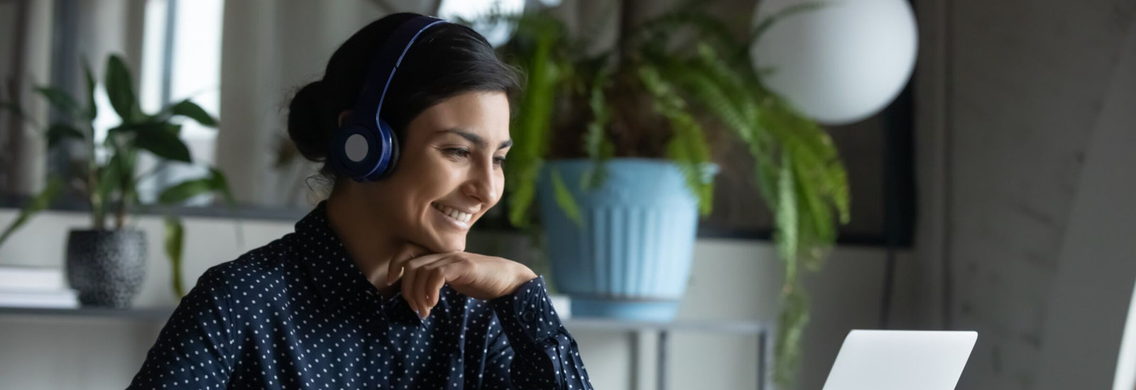 Woman with headphones on working from home on a laptop.